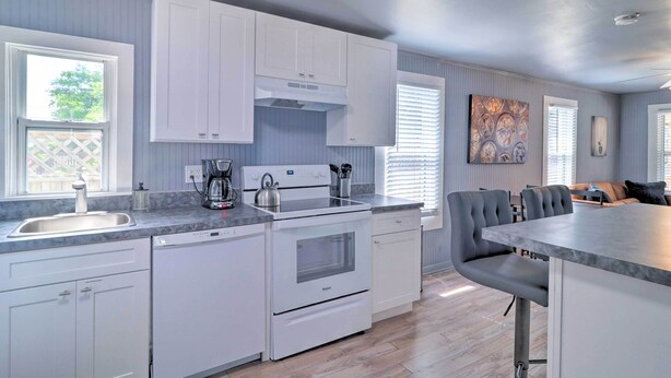 A modern kitchen with white cabinetry, a built-in oven, and a large island with bar stools.
