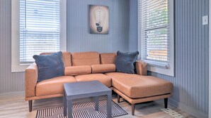 A room with a brown leather sectional sofa, a small table, and a patterned rug.