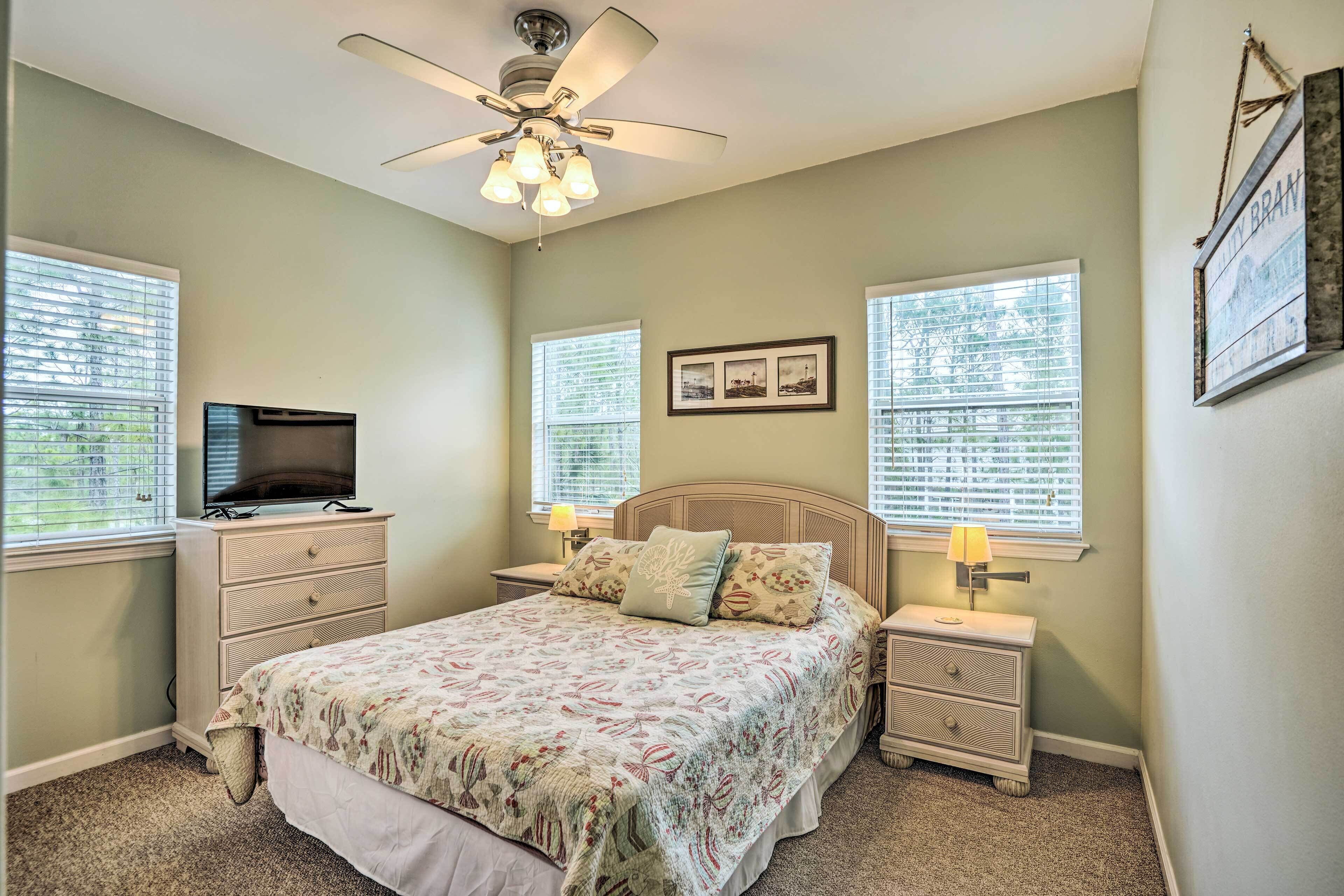 A bedroom with a bed, nightstands, a ceiling fan, and a television on a dresser.