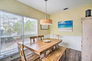 Un espace repas comprenant une table en bois, des chaises et un luminaire suspendu.