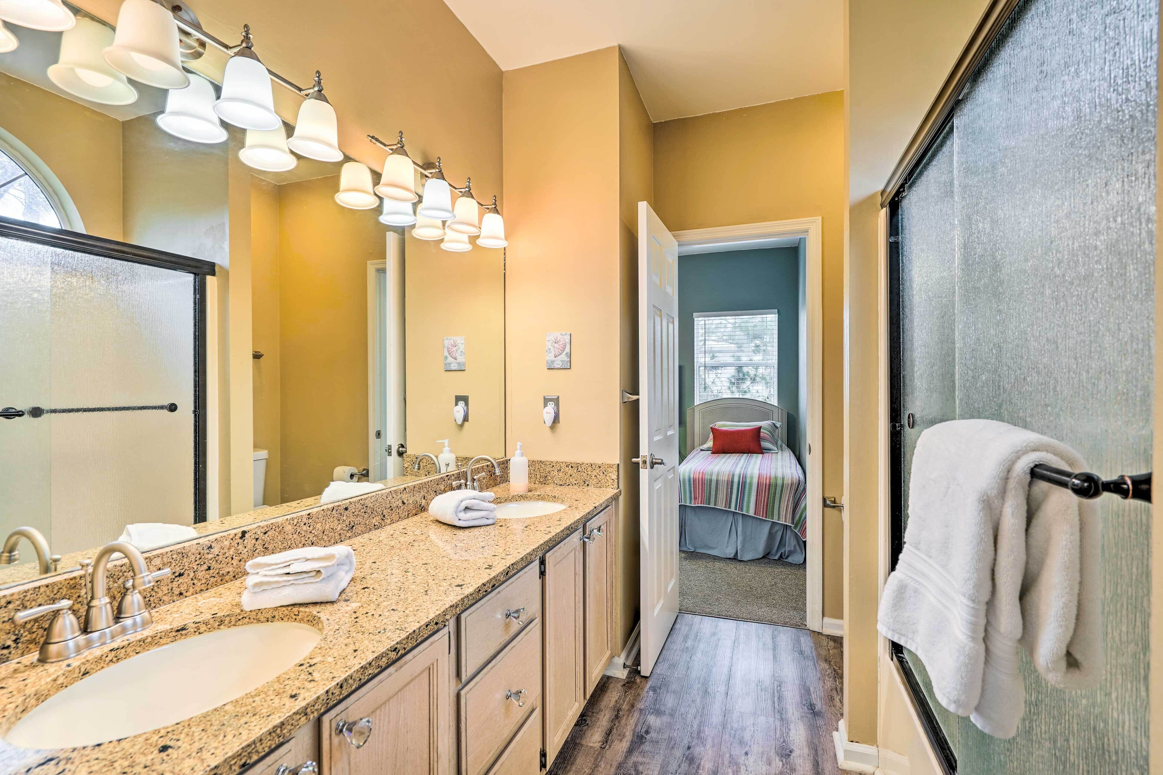 A bathroom with two sinks, a large mirror, and a shower area.