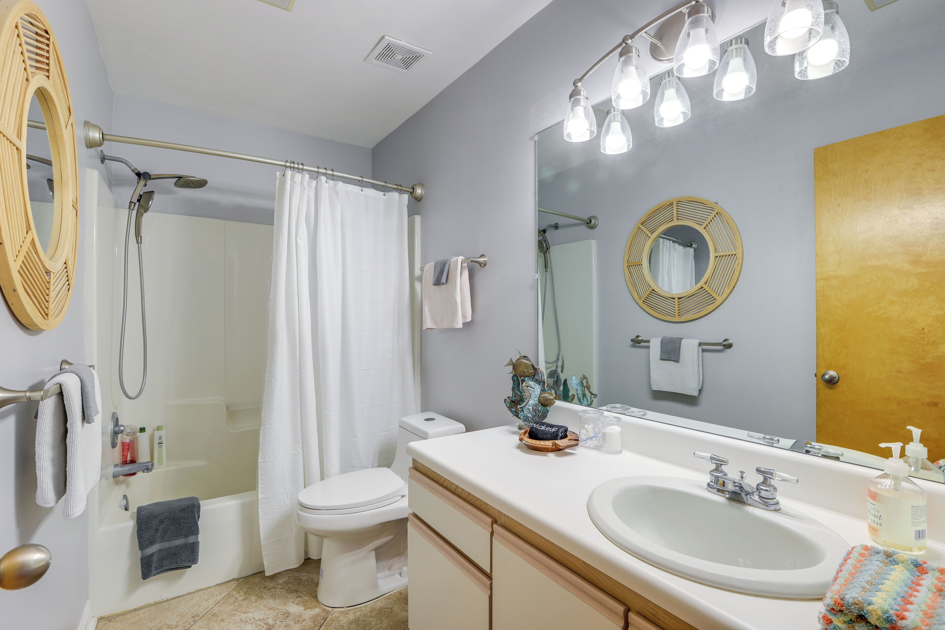 A bathroom with a bathtub, toilet, sink, and a large mirror.