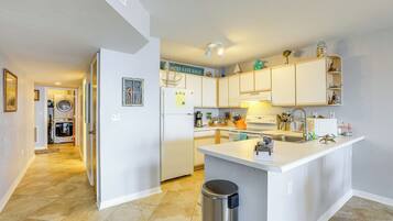 A modern kitchen with white cabinets, a central island, and a view into the laundry area.