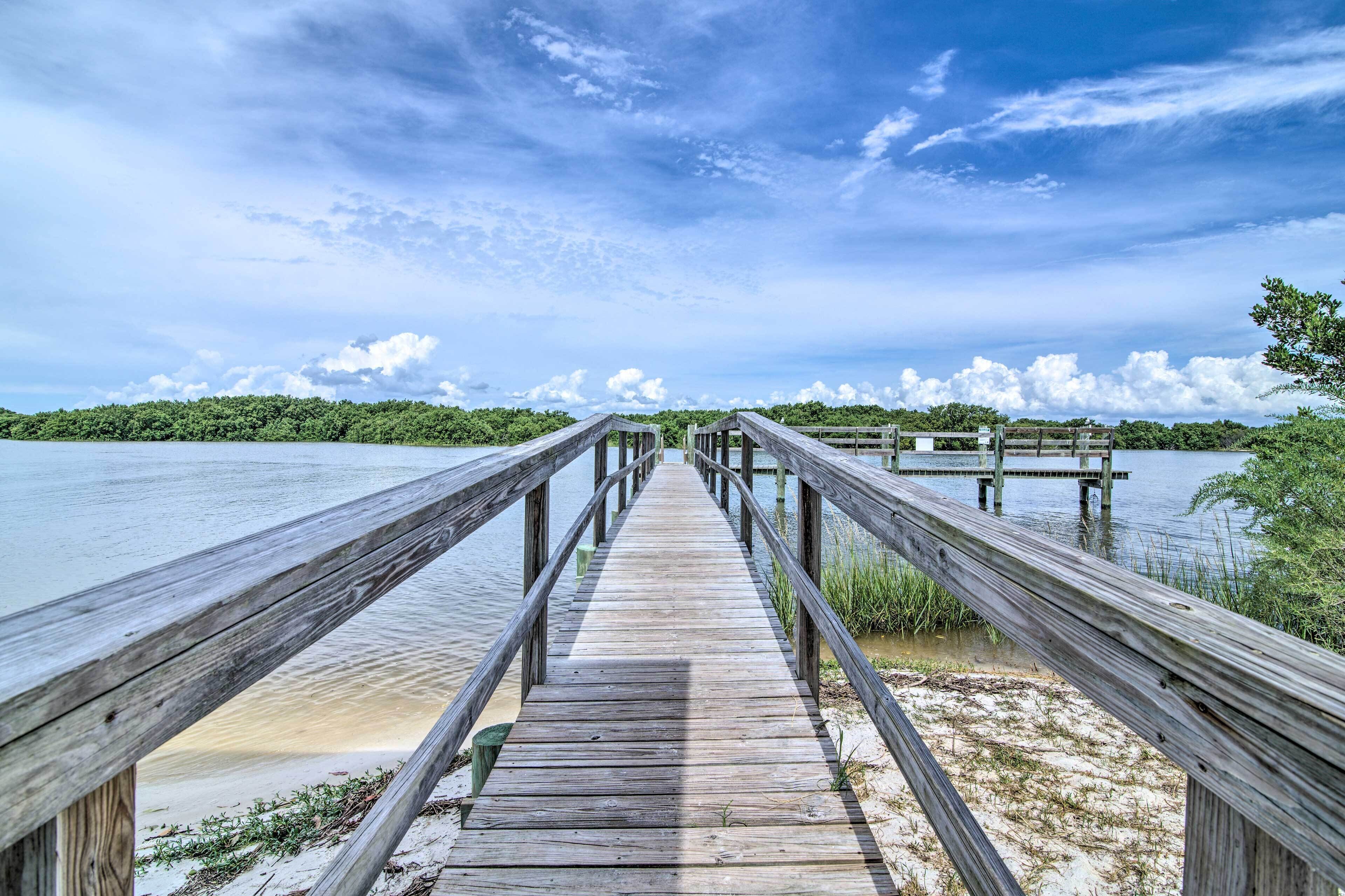 A wooden pier extending into a body of water with a clear sky above.