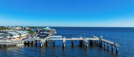 A pier extending into calm waters with buildings and a dock on the left.