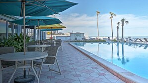 Un espace aménagé au bord de la piscine, avec des parasols, des chaises et un panneau indiquant « DBR ».