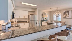 A modern kitchen with granite countertops, stainless steel appliances, and a central island with seating. - Beachfront Fort Walton Beach Condo w/ Pool Access! (Fort Walton Beach)