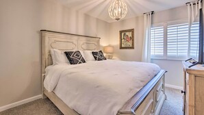 A bedroom with a white bed, a chandelier, a window with blinds, and a picture on the wall. - Beachfront Fort Walton Beach Condo w/ Pool Access! (Fort Walton Beach)