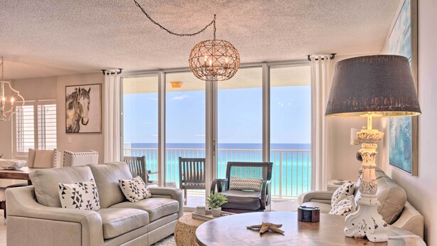 A spacious living room with a large window offering a view of the ocean, a round coffee table, and comfortable seating. - Beachfront Fort Walton Beach Condo w/ Pool Access! (Fort Walton Beach)