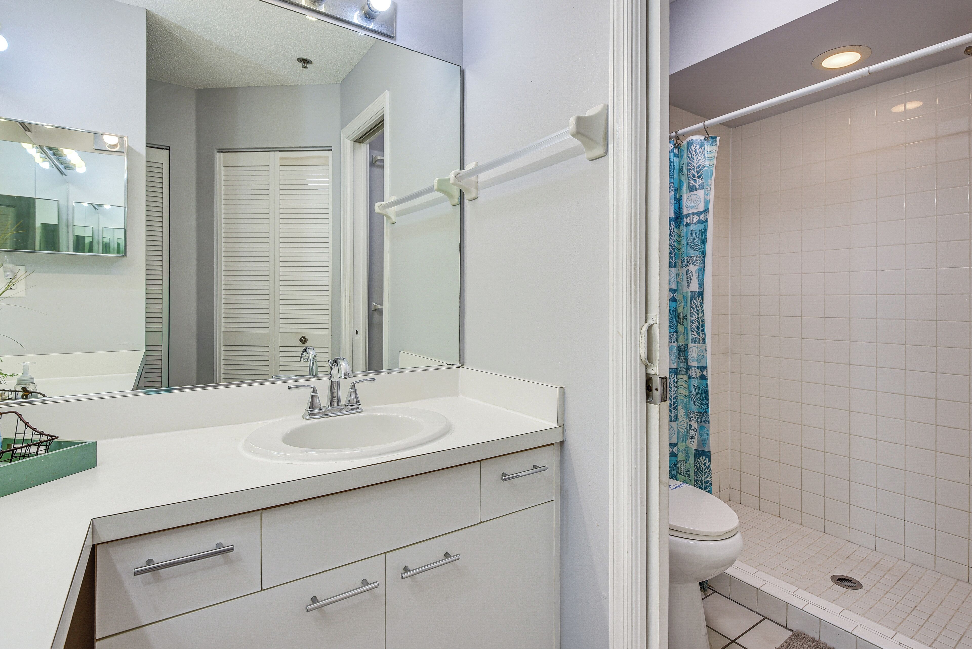 Une salle de bain avec un lavabo blanc, un miroir et des toilettes.