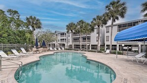 A pool area with lounge chairs and a building in the background.