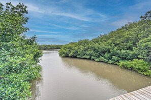 Une rivière bordée d’une végétation luxuriante et verdoyante, avec un quai en bois.