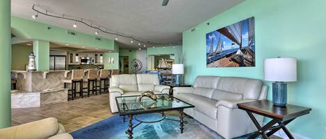 A spacious living area with a glass coffee table, a sofa, and a dining area with chairs.