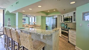 Uma cozinha com ilha de mármore, banquetas e eletrodomésticos modernos.