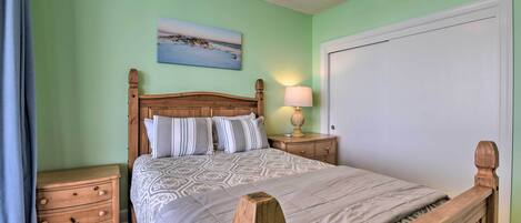 Un dormitorio con una cama de madera, una mesita de noche, una lámpara y un cuadro en la pared.