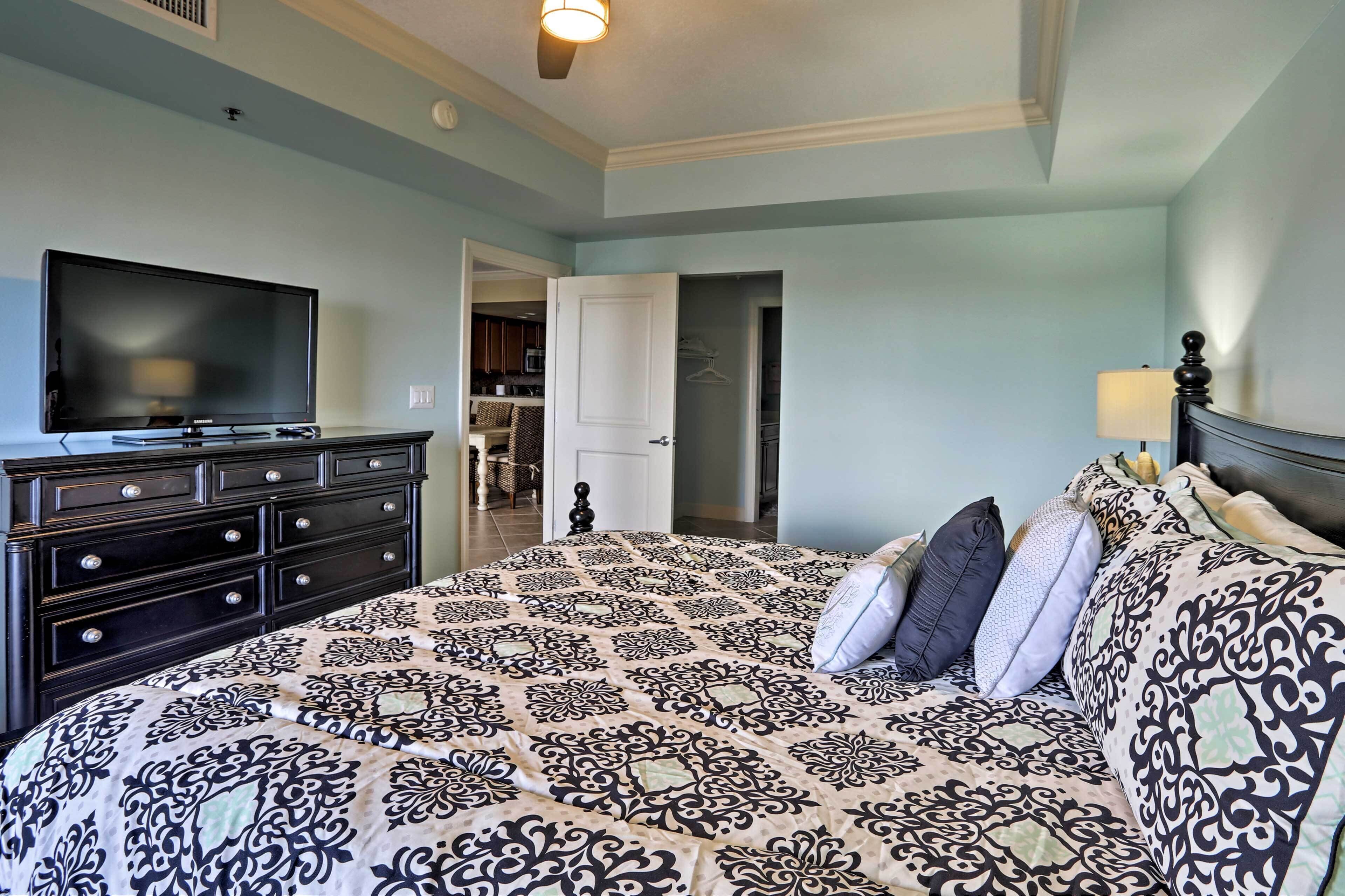 A bedroom with a large bed, a TV, a dresser, and a walk-in closet.