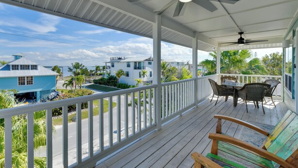 A covered outdoor area with a table and chairs, a wooden bench, and a view of the surrounding neighborhood. - Steps to Ocean & Bay: Bradenton Beach Townhome! (Bradenton Beach)