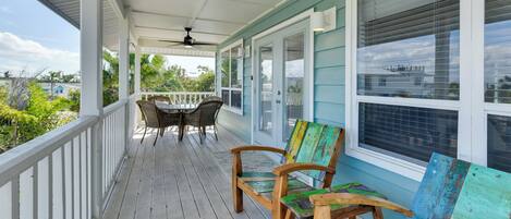 Eine überdachte Veranda mit Deckenventilator, einem Tisch mit Stühlen und einer Bank.