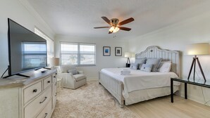 A bedroom with a bed, a ceiling fan, a TV, a dresser, a chair, and a lamp. - Steps to Ocean & Bay: Bradenton Beach Townhome! (Bradenton Beach)