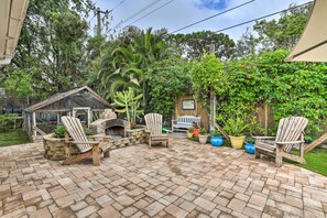 Un espace patio avec un sol en briques, des chaises en bois, une petite structure en bois et des plantes en pot.
