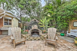 A patio with a stone fireplace, two Adirondack chairs, and a wooden fence. - Bradenton Home w/ Beautiful Yard: 4 Mi to Downtown (Bradenton)
