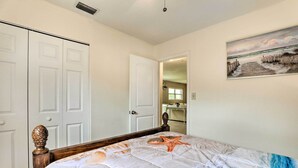 Een slaapkamer met een bed, witte deuren, een schilderij en uitzicht op een andere kamer.