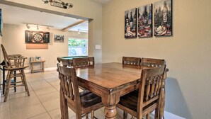 Een eetruimte met een houten tafel en stoelen, een dartbord en wanddecoratie.