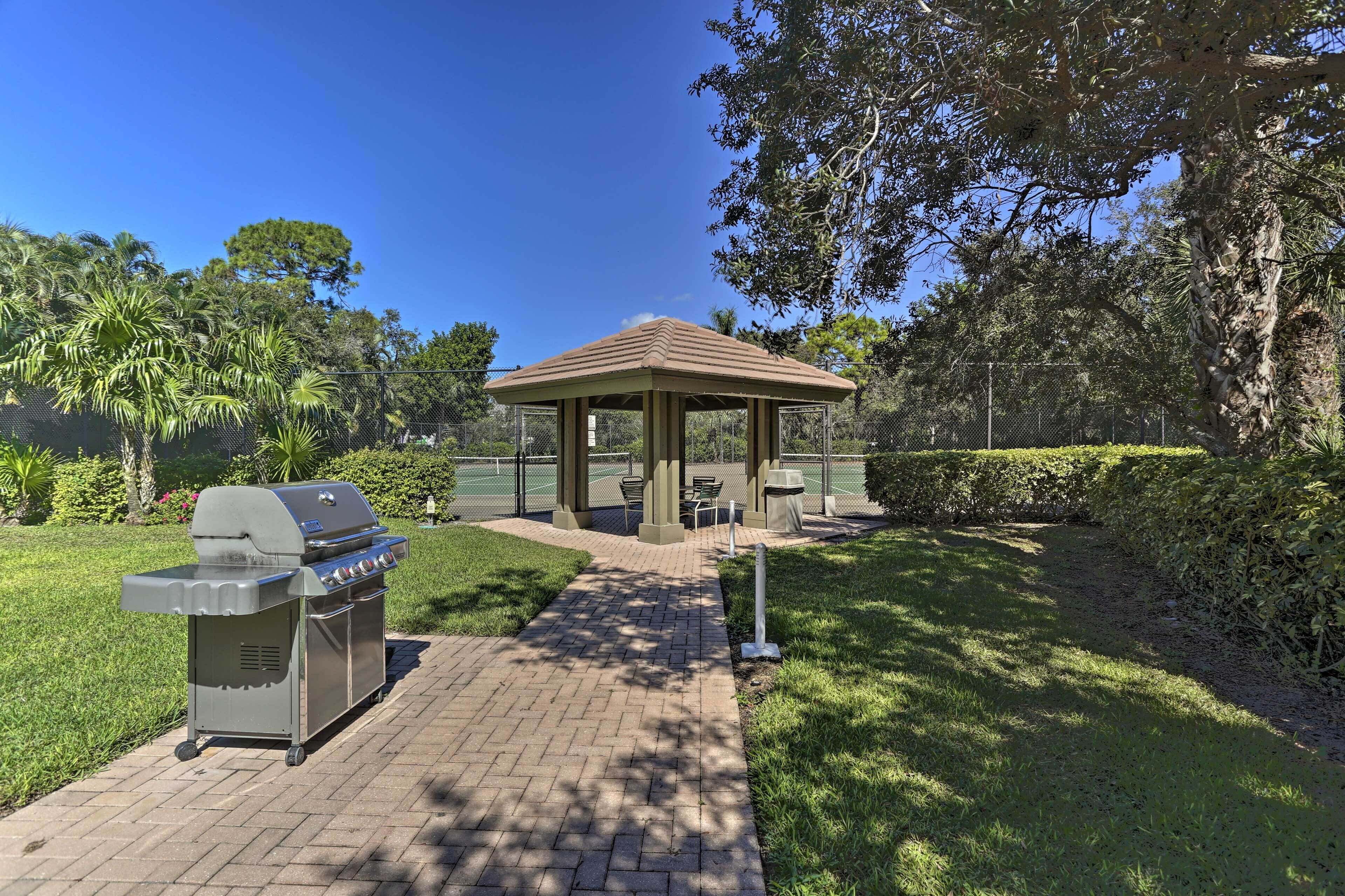 A gazebo with a grill and seating area in a park setting.