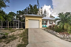 A single-story house with a garage, a covered patio area, and a well-maintained garden with various plants and a small pond.