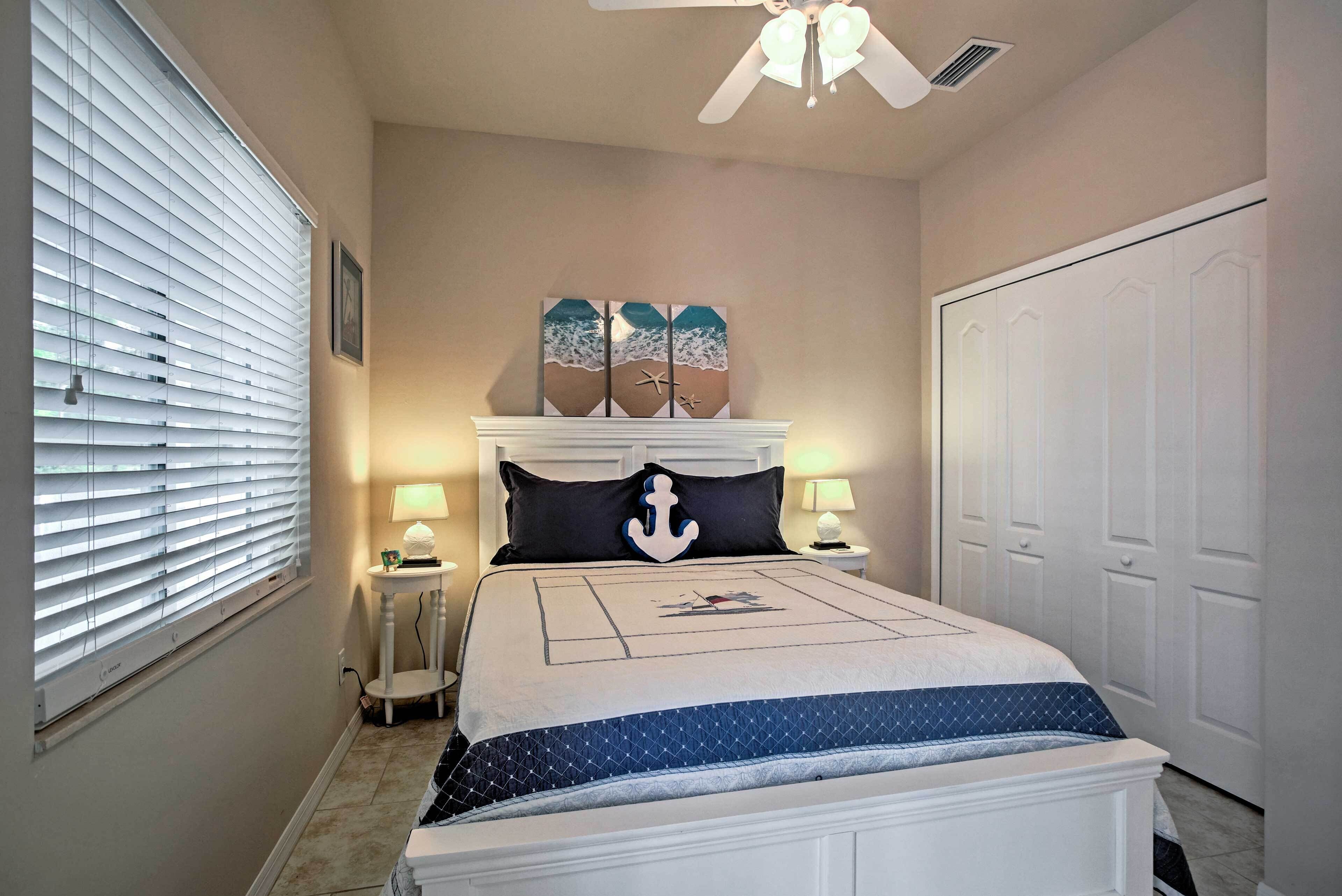 Une chambre à coucher avec un lit, un ventilateur de plafond, une table de chevet, une lampe et une porte.