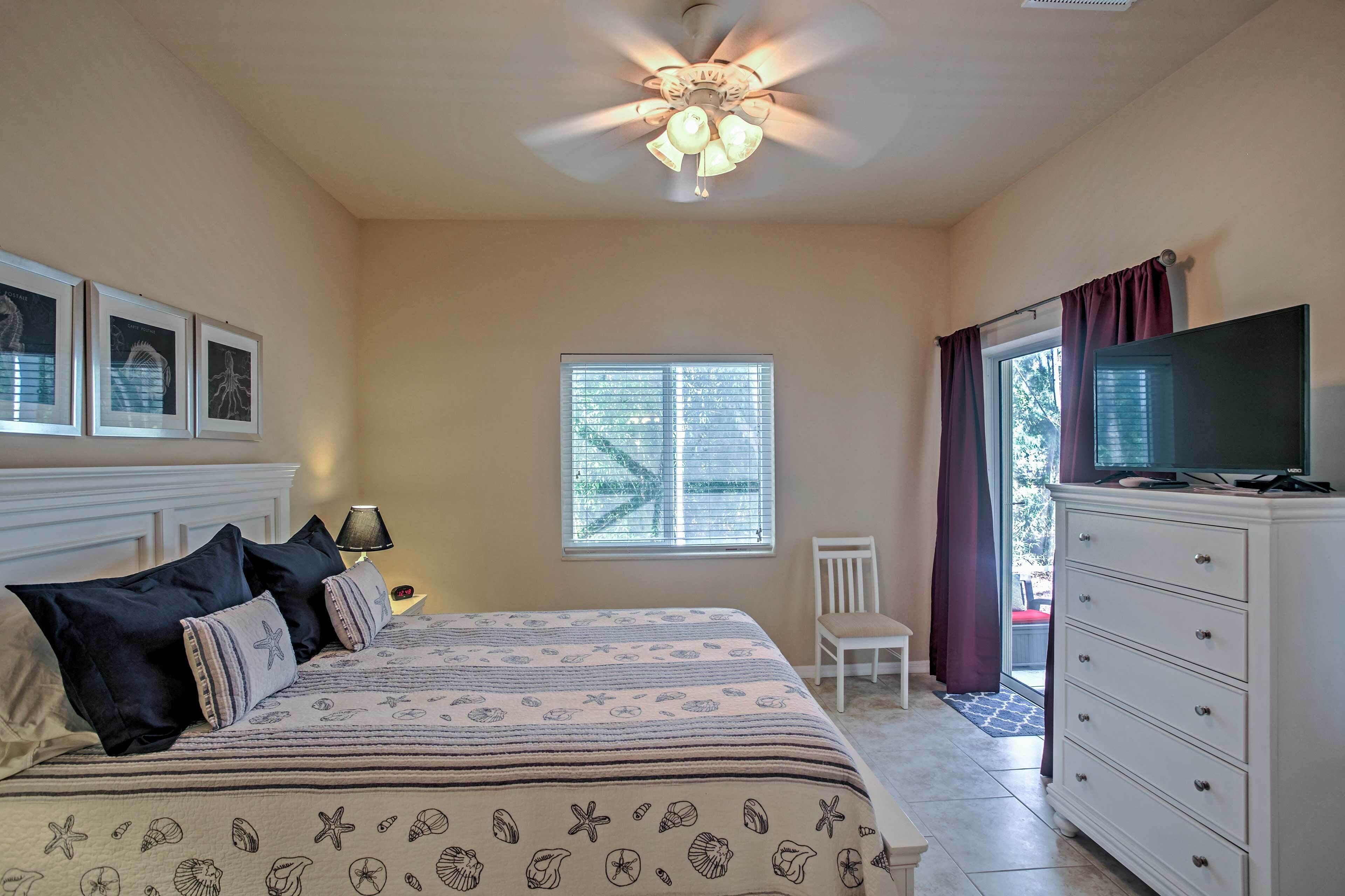 A bedroom with a bed, a ceiling fan, a TV on a dresser, and a window with blinds.