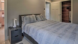 A bedroom with a bed, nightstand, and a wooden closet.