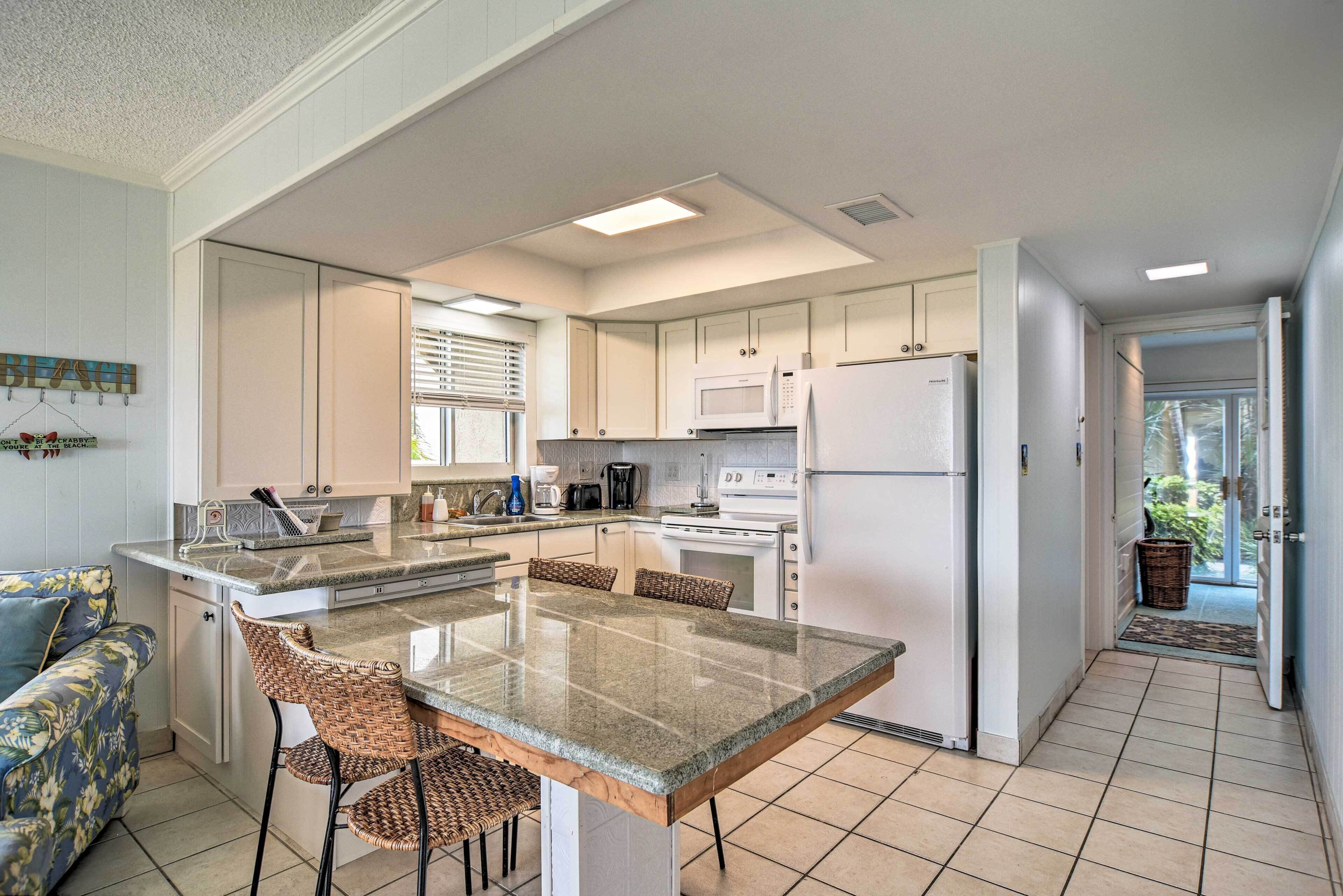 A modern kitchen with a central island, white cabinetry, and a dining area with wicker chairs.
