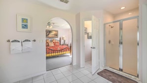 A hotel room with a bed, a shower, and a hallway leading to another room. - Pool + Game Room, 5 Mi to Disney: Kissimmee Home! (Kissimmee)