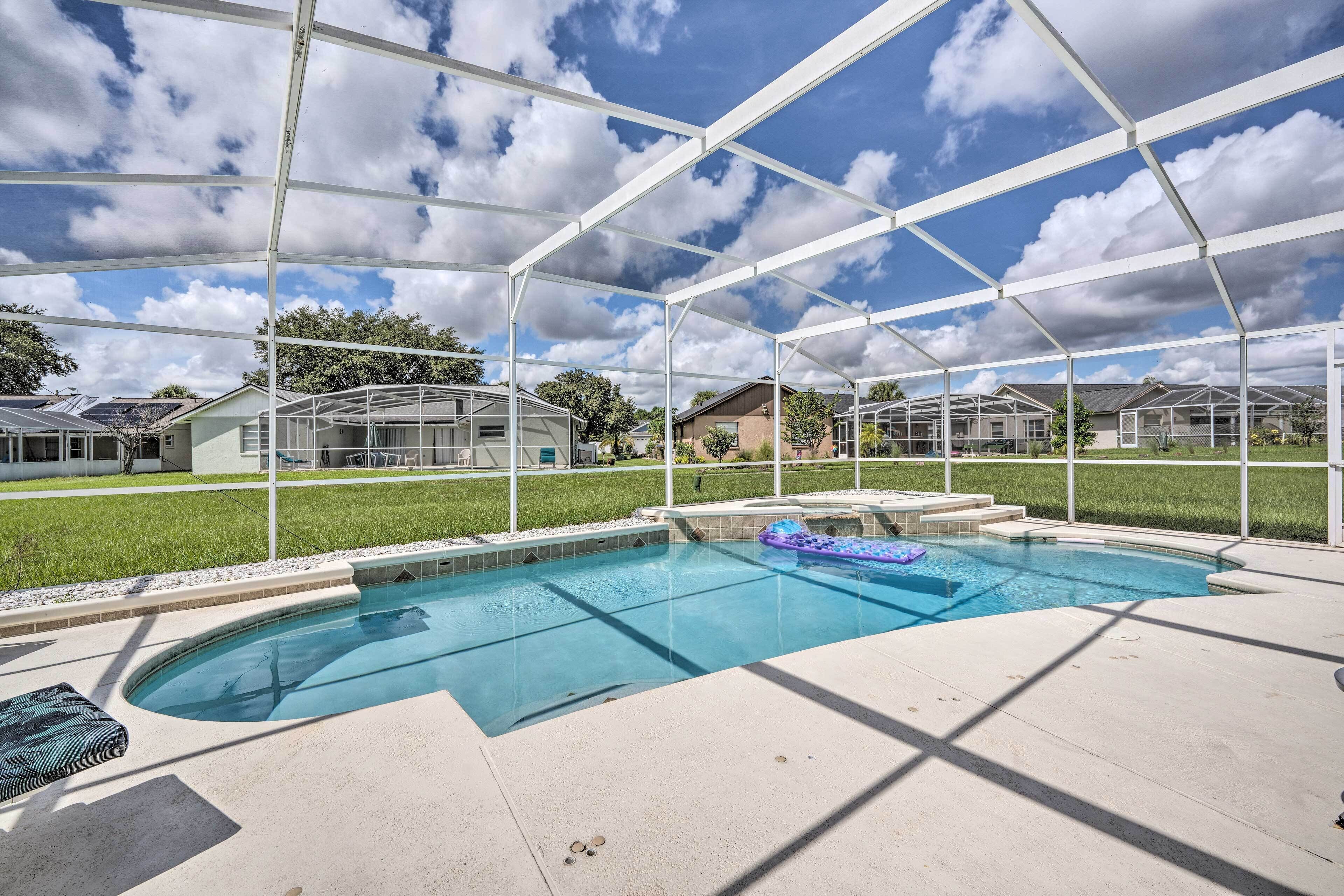 A swimming pool with a clear blue sky and clouds above, surrounded by a white metal structure.