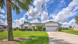 A single-story house with a garage, surrounded by a well-maintained lawn and a palm tree. - Pool + Game Room, 5 Mi to Disney: Kissimmee Home! (Kissimmee)