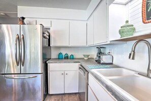 A modern kitchen with stainless steel appliances, white cabinetry, and a tiled backsplash. - Beachy Bradenton Vacation Home Near Ocean! (Bradenton)