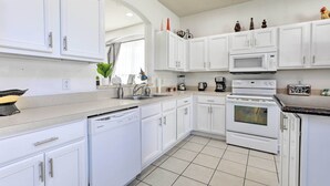 Una cocina moderna con armarios blancos, lavavajillas, microondas y horno.