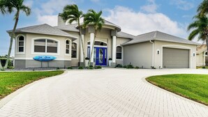 Uma casa moderna de dois andares com telhado curvo, porta azul e garagem.