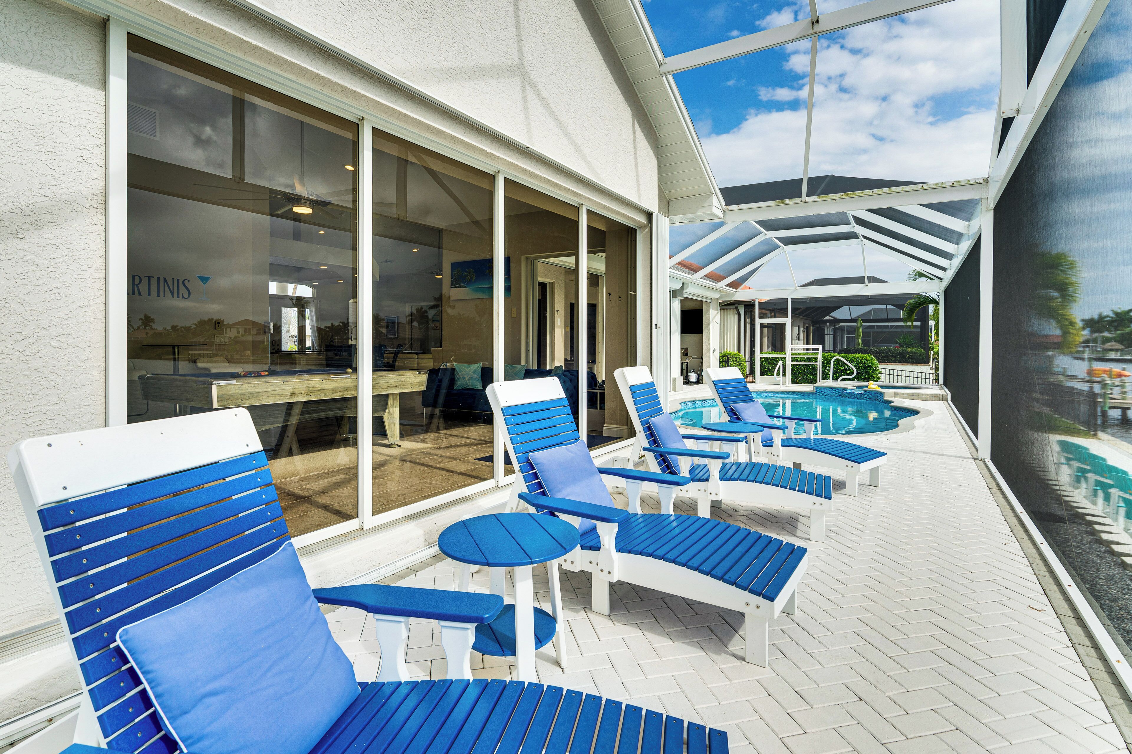Zona de piscina con sillones de descanso y una piscina cubierta con cristal.