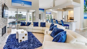 Uma sala de estar espaçosa com um sofá branco modular grande, um tapete felpudo azul e uma lareira.