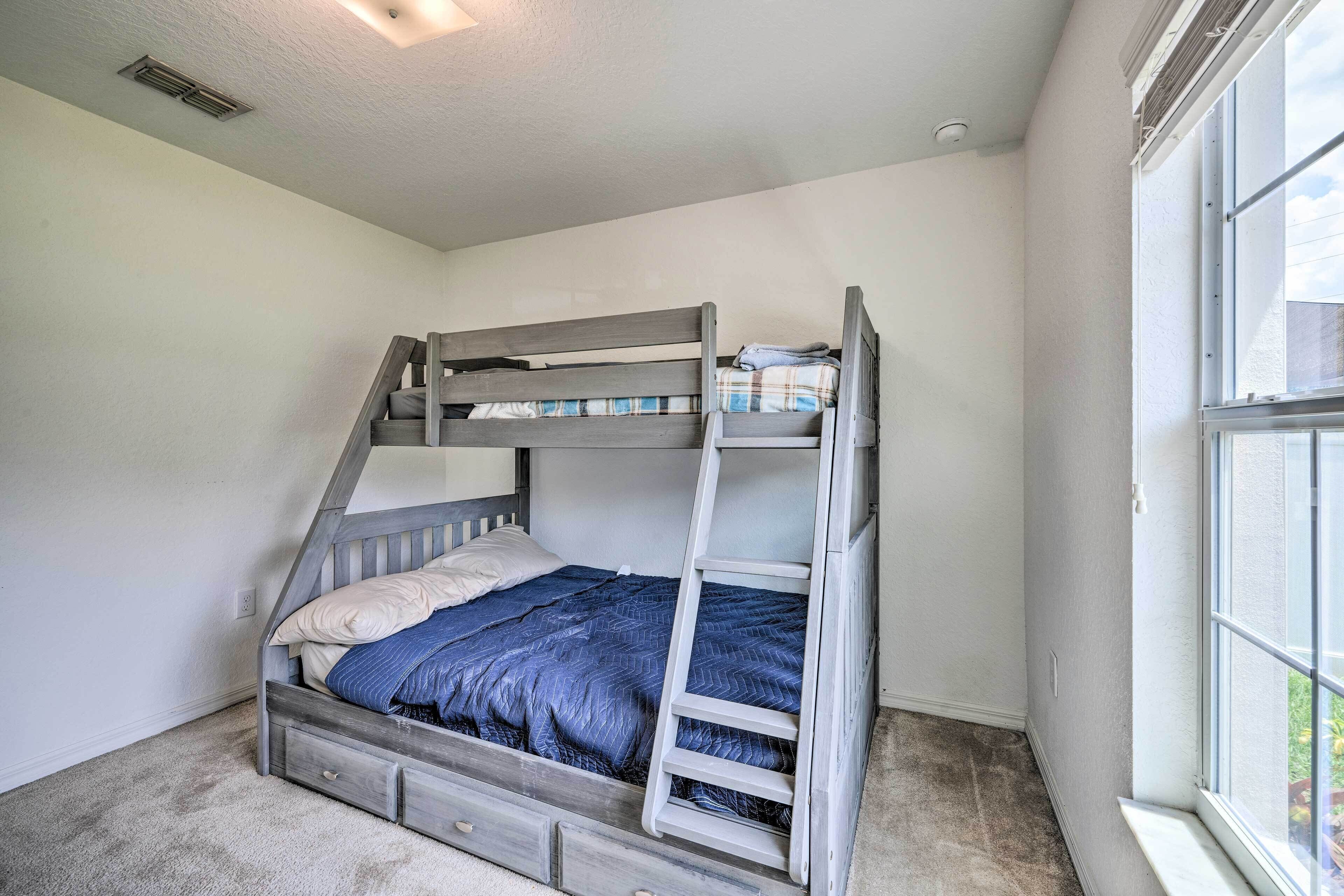 A bunk bed with a ladder, a window, and a ceiling vent.