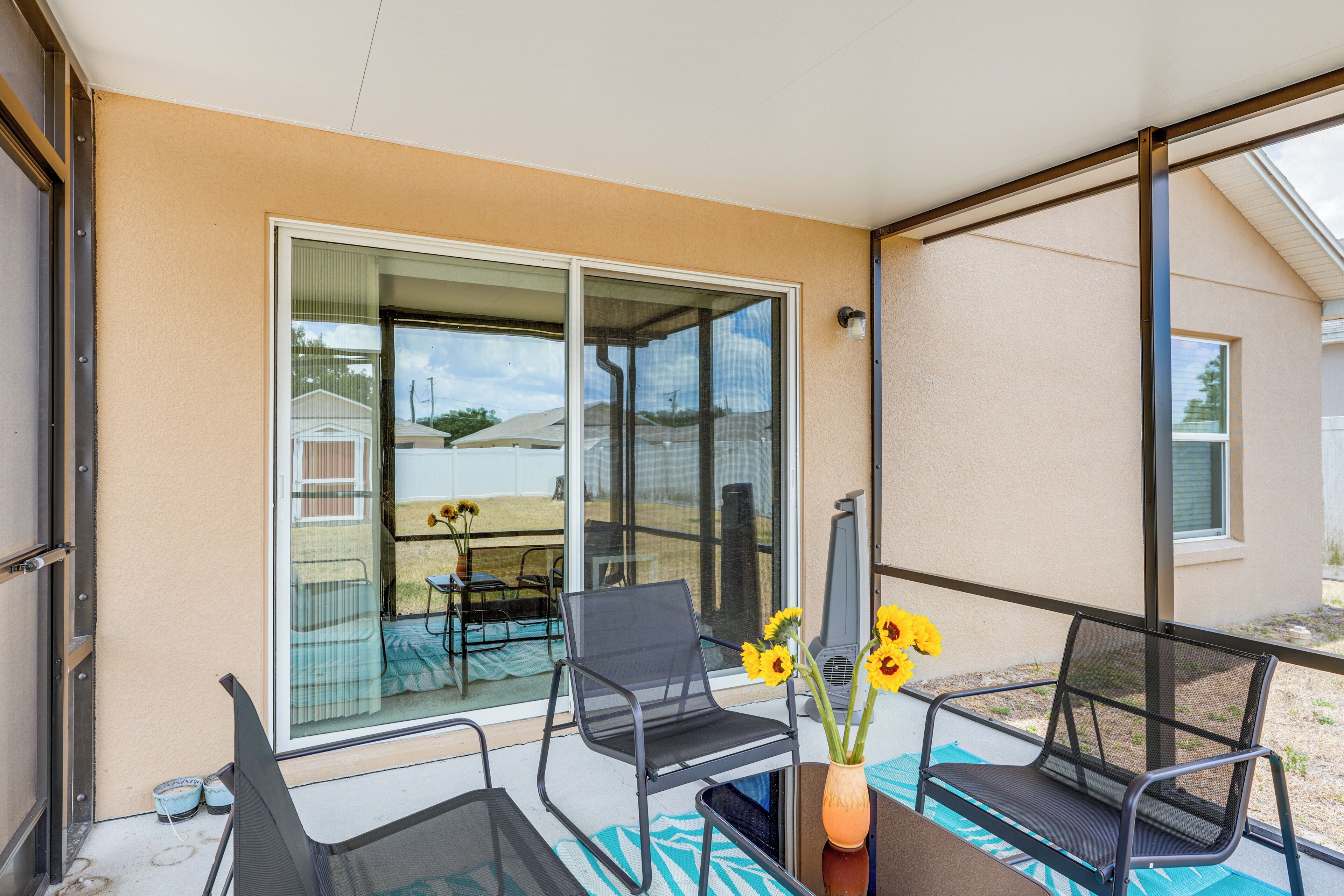 Ein Balkon mit zwei Stühlen, einem Tisch und einer Vase mit Sonnenblumen.