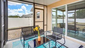 A balcony with a glass table, chairs, and a vase with flowers. - Bright Cypress Gardens Home Near Legoland! (Winter Haven)