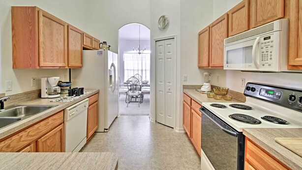 A kitchen with wooden cabinets, a white stove, and a microwave. - Bright Spring Hill Home: 5 Mi to Weeki Wachee Park (Spring Hill)