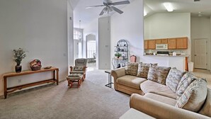 A spacious living room with a beige sofa, a wooden bench, and a ceiling fan. - Bright Spring Hill Home: 5 Mi to Weeki Wachee Park (Spring Hill)