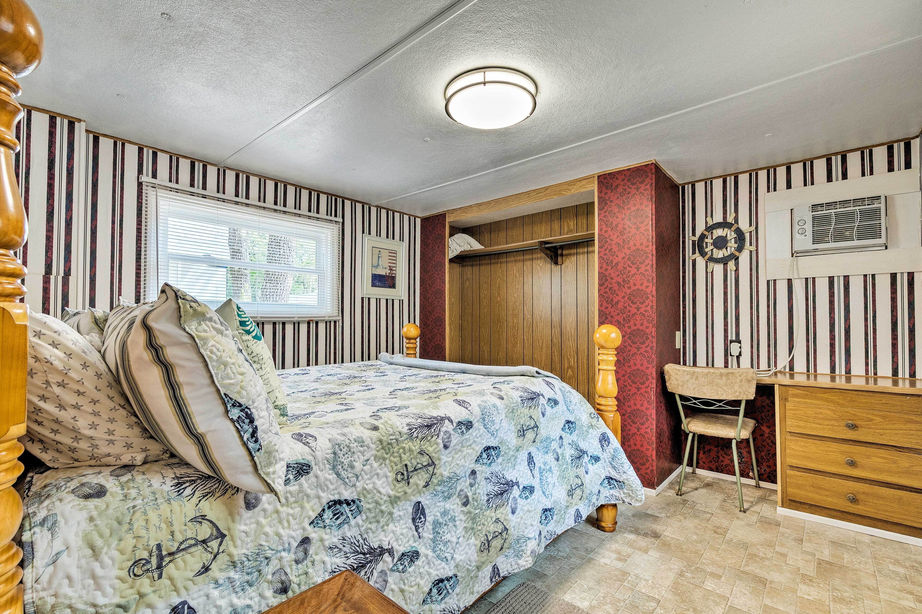 A bedroom with a bed, dresser, and a window with blinds.