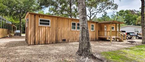 A wooden cabin with a deck, a covered porch, and a small attached structure.