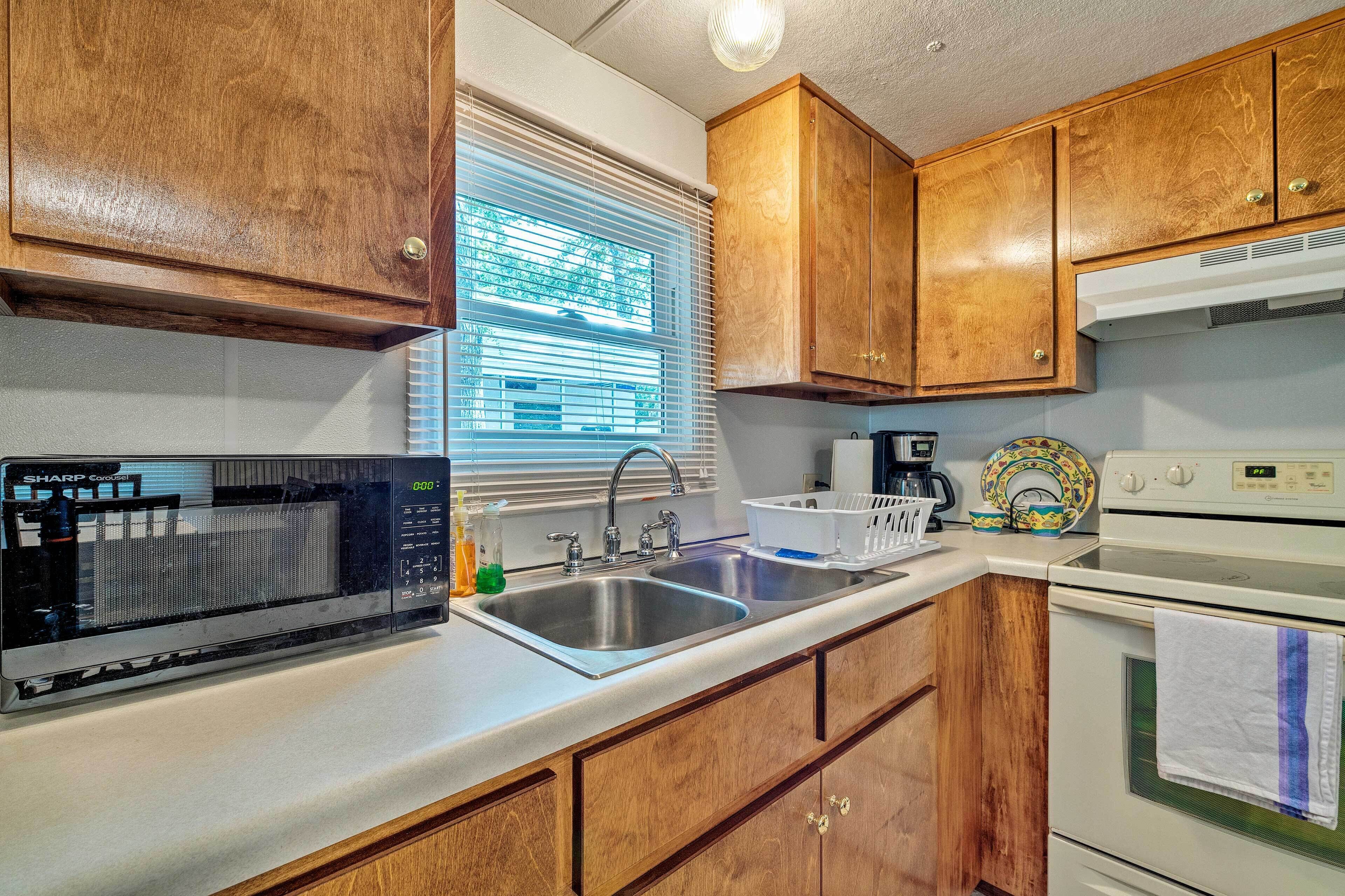 A kitchen with wooden cabinets, a stainless steel sink, a microwave, and a stove.
