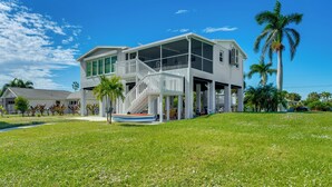 A two-story house with a covered porch and a boat dock. - Canalfront St James City Home w/ Unique View (Saint James City)